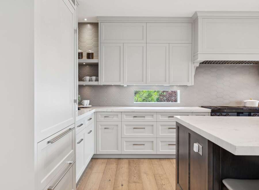 Experience modern luxury in this stunning kitchen, featuring sleek white cabinetry and a chic hexagonal tile backsplash.