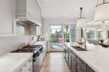 Experience luxury in this stunning modern kitchen, featuring a sleek gas range with a hexagonal tile backsplash and a spacious island with a double sink.