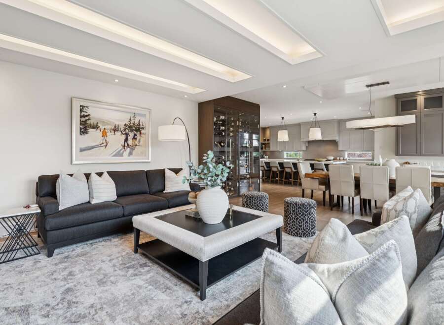 Experience luxury living in this open-concept space, featuring a spacious living area with a large sectional sofa and a stylish coffee table, seamlessly flowing into a modern kitchen and dining area.
