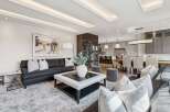Experience luxury living in this open-concept space, featuring a spacious living area with a large sectional sofa and a stylish coffee table, seamlessly flowing into a modern kitchen and dining area.