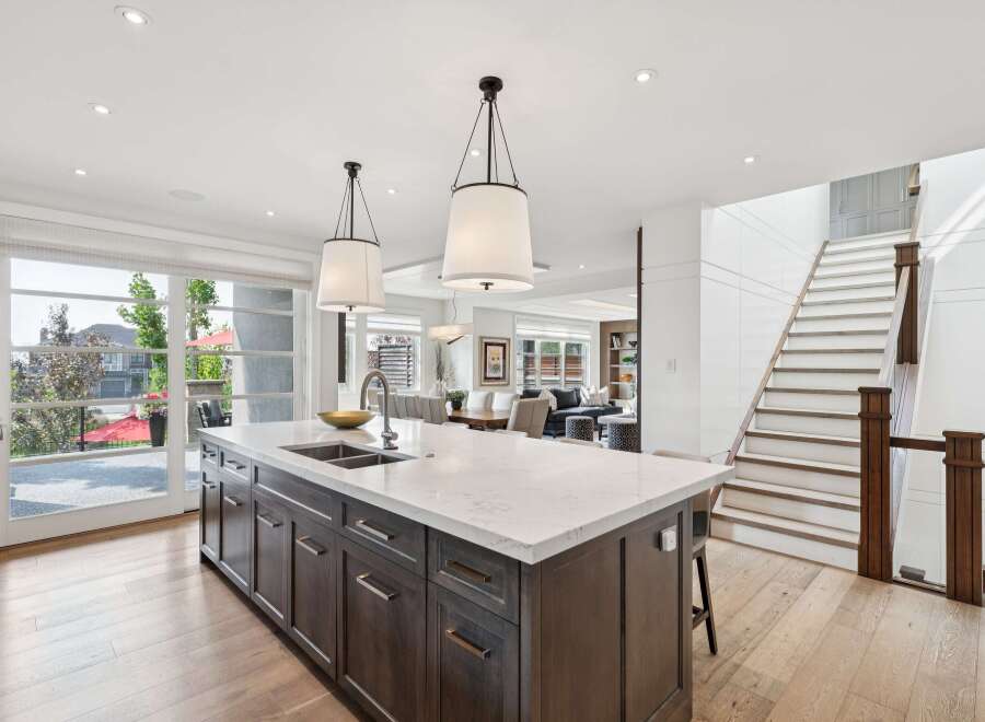 Experience luxury living in this stunning modern kitchen, featuring a large marble island with a double sink and sleek dark wood cabinetry.