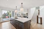 Experience luxury living in this stunning modern kitchen, featuring a large marble island with a double sink and sleek dark wood cabinetry.