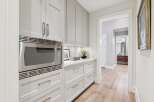 Discover this beautifully appointed kitchen pantry, featuring sleek grey cabinetry and a modern stainless steel microwave.