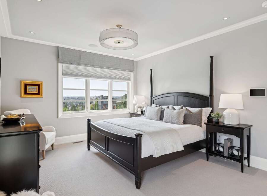 Experience luxury in this master suite featuring a grand four-poster bed adorned with plush pillows and a crisp white duvet.