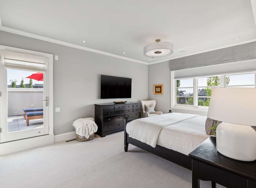Experience luxury in this master bedroom featuring a king-sized bed, a large dresser, and a wall-mounted TV.