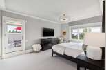 Experience luxury in this master bedroom featuring a king-sized bed, a large dresser, and a wall-mounted TV.