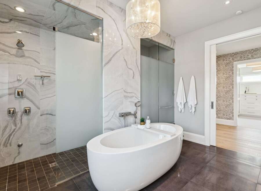 Indulge in luxury with this stunning master bathroom, featuring a spacious walk-in shower with elegant marble tile and multiple shower heads.