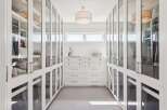 Step into this impeccably organized walk-in closet, featuring floor-to-ceiling glass-fronted cabinetry for a sophisticated display of your wardrobe.