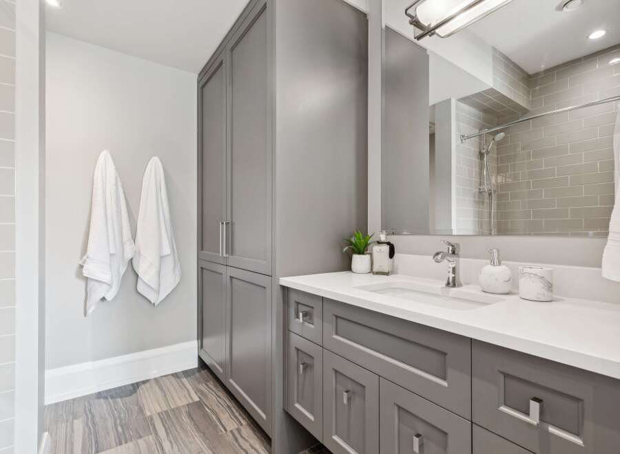 Experience modern elegance in this beautifully appointed bathroom, featuring a sleek grey vanity with ample storage and a pristine white countertop.