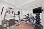 Elevate your fitness routine in this state-of-the-art home gym, featuring a Precor elliptical, a NordicTrack rower, and a comprehensive dumbbell rack.