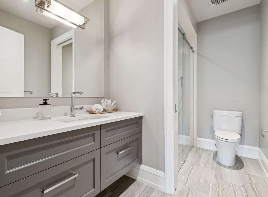 Experience modern luxury in this stunning bathroom featuring a sleek vanity with ample storage and a pristine white countertop.