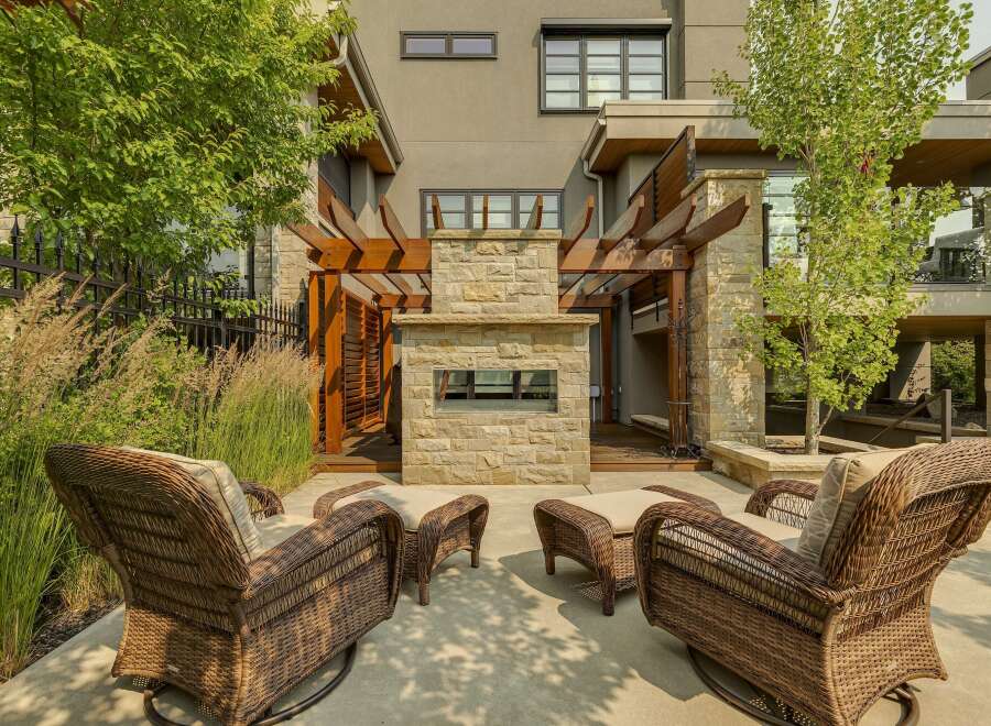 Experience luxurious outdoor living with this stunning patio featuring a modern stone fireplace and comfortable wicker seating.