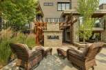 Experience luxurious outdoor living with this stunning patio featuring a modern stone fireplace and comfortable wicker seating.
