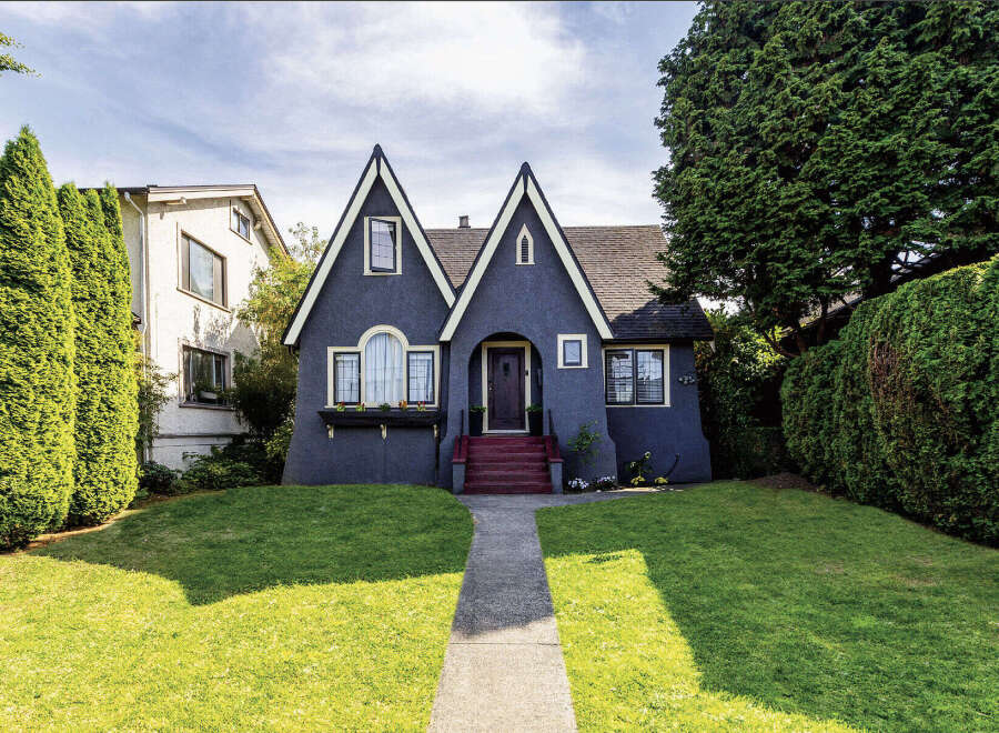 Charming dark blue Tudor-style home with distinctive pointed gables and a welcoming arched entryway.