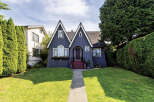 Charming dark blue Tudor-style home with distinctive pointed gables and a welcoming arched entryway.