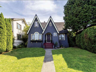 Charming dark blue Tudor-style home with distinctive pointed gables and a welcoming arched entryway.