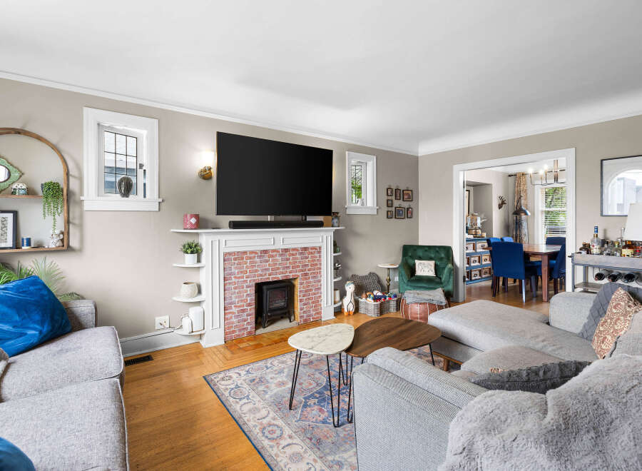 Step into this inviting living room featuring a cozy brick fireplace and a large flat-screen TV, perfect for entertainment.