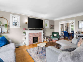 Step into this inviting living room featuring a cozy brick fireplace and a large flat-screen TV, perfect for entertainment.