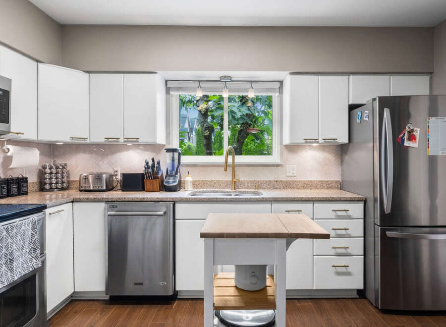 Discover this beautifully updated kitchen featuring sleek white cabinetry and modern stainless steel appliances.