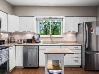 Discover this beautifully updated kitchen featuring sleek white cabinetry and modern stainless steel appliances.