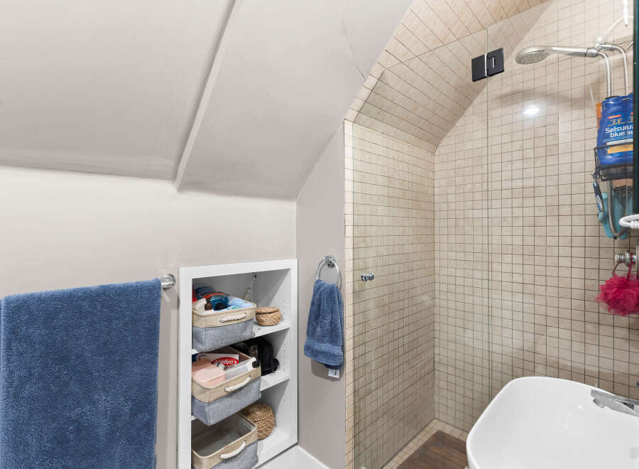 Discover this charming bathroom featuring a spacious tiled shower with a glass enclosure and a modern showerhead.