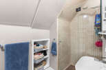 Discover this charming bathroom featuring a spacious tiled shower with a glass enclosure and a modern showerhead.
