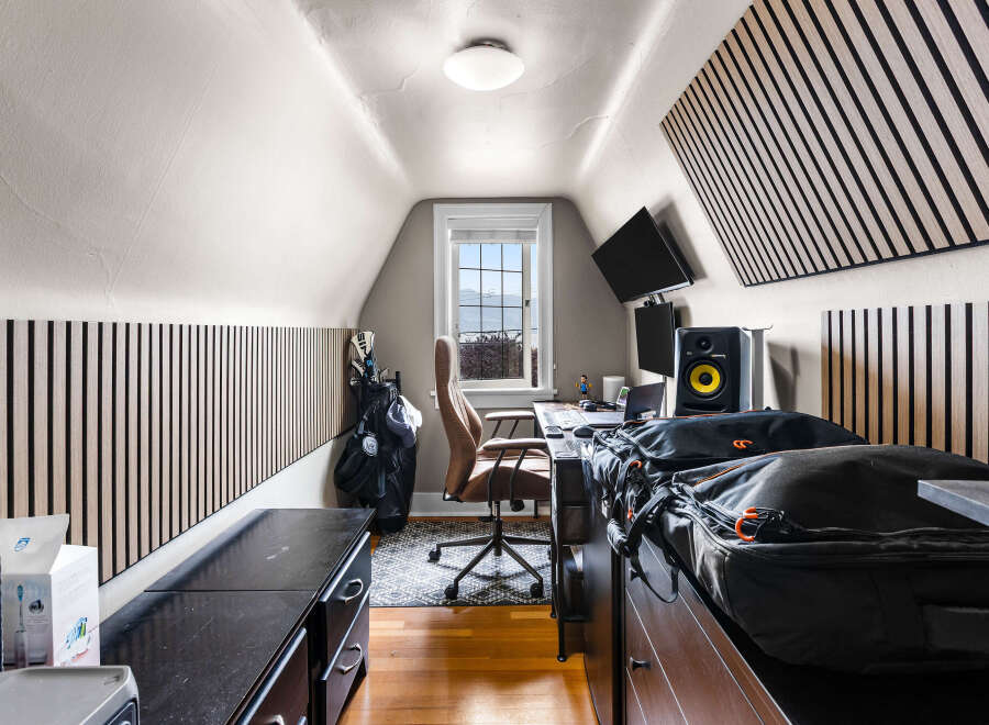 This attic room offers a functional workspace with a desk, chair, and dual monitors, perfect for remote work or creative projects.