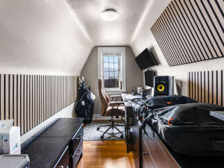 This attic room offers a functional workspace with a desk, chair, and dual monitors, perfect for remote work or creative projects.
