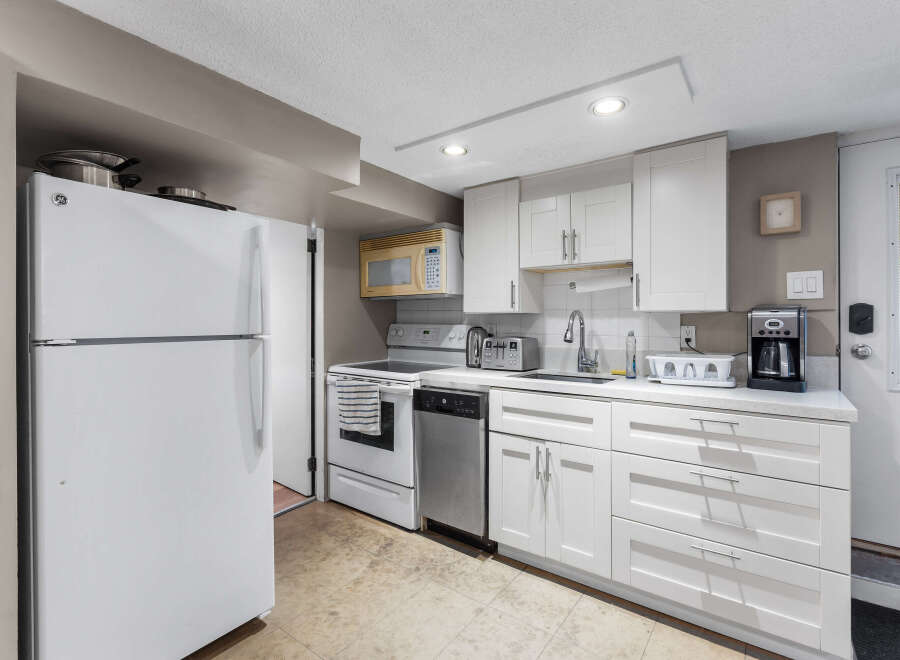 Discover this charming kitchen featuring a full-size refrigerator, a convenient microwave, and a modern dishwasher.