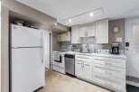 Discover this charming kitchen featuring a full-size refrigerator, a convenient microwave, and a modern dishwasher.