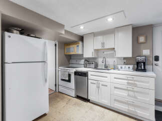 Discover this charming kitchen featuring a full-size refrigerator, a convenient microwave, and a modern dishwasher.