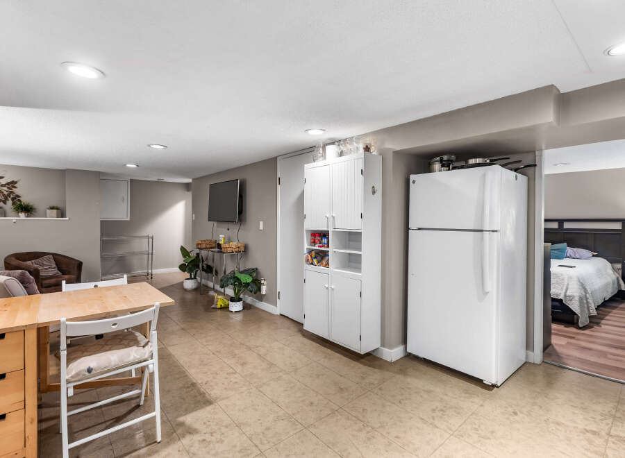 Discover comfortable living in this versatile space featuring a compact kitchen area with a refrigerator and ample storage cabinets.