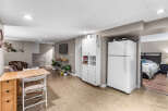 Discover comfortable living in this versatile space featuring a compact kitchen area with a refrigerator and ample storage cabinets.