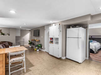 Discover comfortable living in this versatile space featuring a compact kitchen area with a refrigerator and ample storage cabinets.