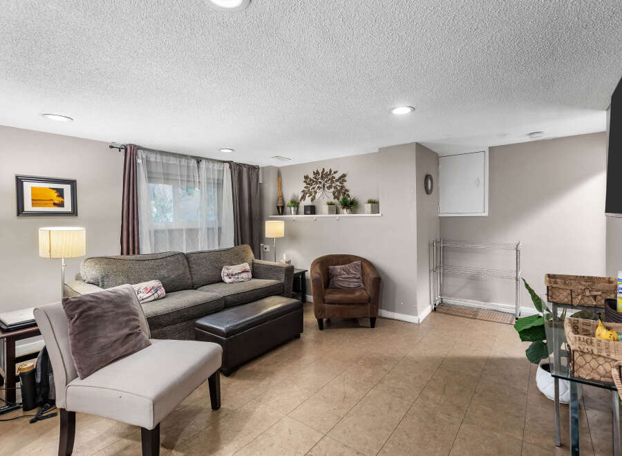 This inviting living room features a comfortable sectional sofa, a plush armchair, and an ottoman, perfect for relaxing.