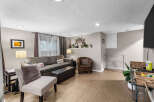 This inviting living room features a comfortable sectional sofa, a plush armchair, and an ottoman, perfect for relaxing.