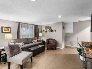 This inviting living room features a comfortable sectional sofa, a plush armchair, and an ottoman, perfect for relaxing.