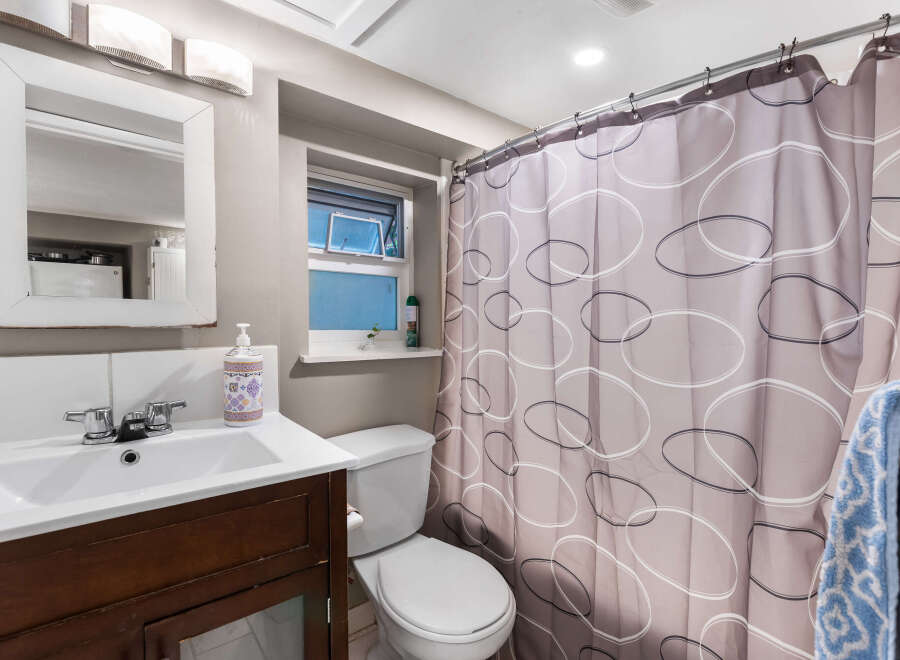 This charming bathroom features a clean white vanity with a modern chrome faucet, complemented by a matching toilet.