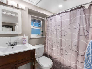 This charming bathroom features a clean white vanity with a modern chrome faucet, complemented by a matching toilet.