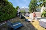 Enjoy outdoor living in this charming backyard featuring a spacious patio area with a dining set and a comfortable outdoor sofa.