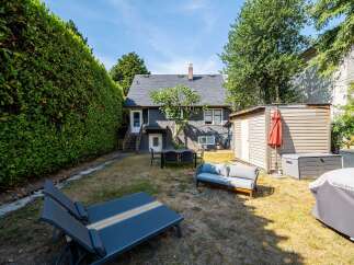 Enjoy outdoor living in this charming backyard featuring a spacious patio area with a dining set and a comfortable outdoor sofa.