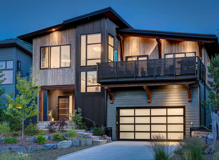 Experience modern mountain living in this stunning architectural home, featuring a striking blend of natural wood and dark corrugated metal siding.