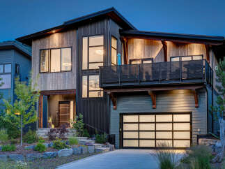 Experience modern mountain living in this stunning architectural home, featuring a striking blend of natural wood and dark corrugated metal siding.