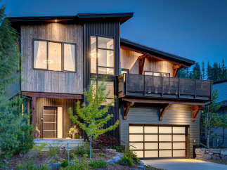 Experience modern mountain living in this stunning architectural home, featuring a striking blend of natural wood and dark corrugated metal siding.