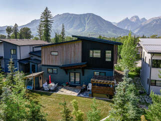 Experience modern mountain living in this stunning home, featuring a unique architectural design with wood and dark siding accents.