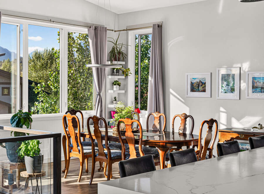 Experience elegant dining in this beautifully appointed space, featuring a classic wooden dining set bathed in natural light from large windows.