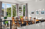 Experience elegant dining in this beautifully appointed space, featuring a classic wooden dining set bathed in natural light from large windows.
