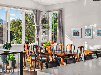Experience elegant dining in this beautifully appointed space, featuring a classic wooden dining set bathed in natural light from large windows.