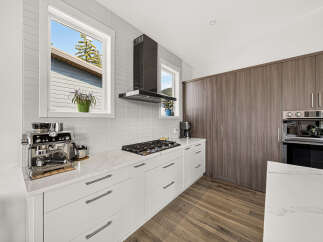 Experience modern kitchen luxury with sleek white cabinetry, a marble countertop, and a professional-grade gas range.
