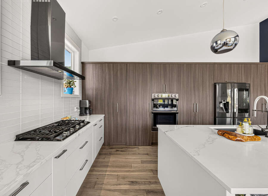 Experience modern luxury in this stunning kitchen, featuring sleek white cabinetry and a marble-patterned countertop.